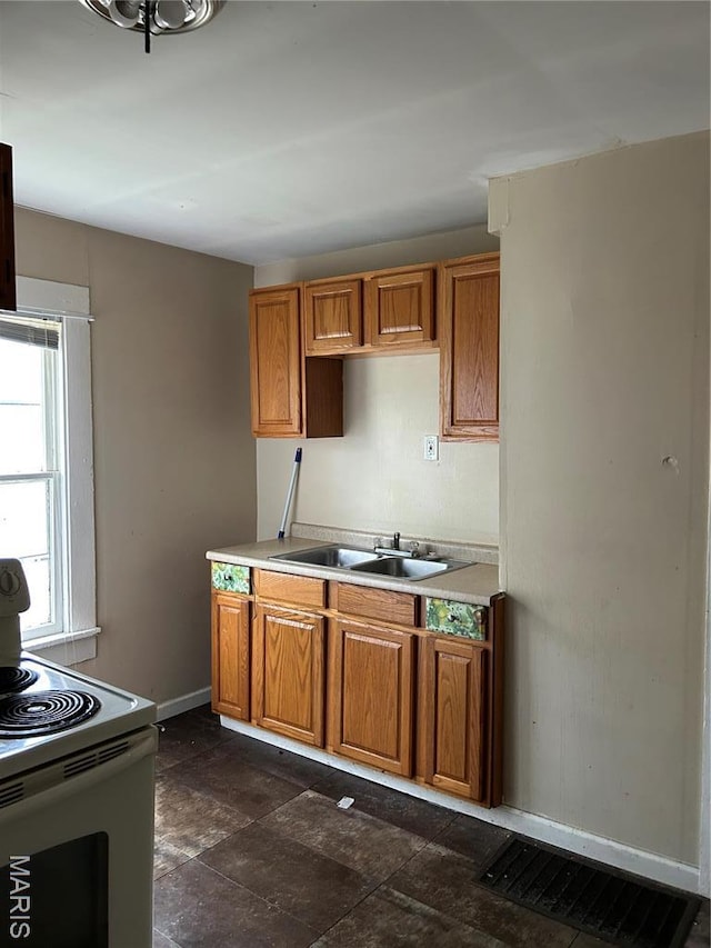 122 Fermo Ave, Ferguson, MO 63135 - kitchen featuring range with electric cooktop, brown cabinets, light countertops, and baseboards