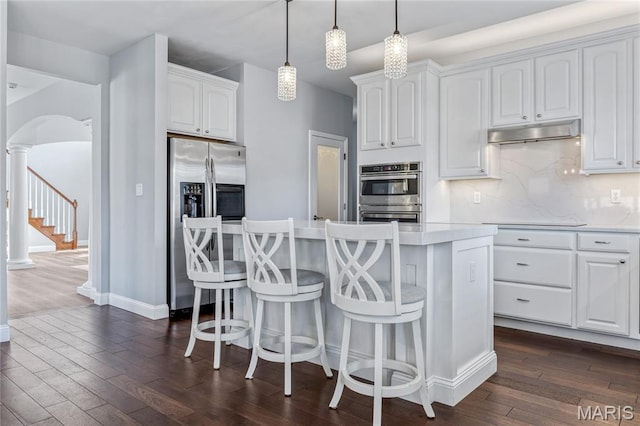 2 Pearview Ct, Saint Peters, MO 63376 - kitchen with appliances with stainless steel finishes, dark wood finished floors, under cabinet range hood, a kitchen island, and arched walkways