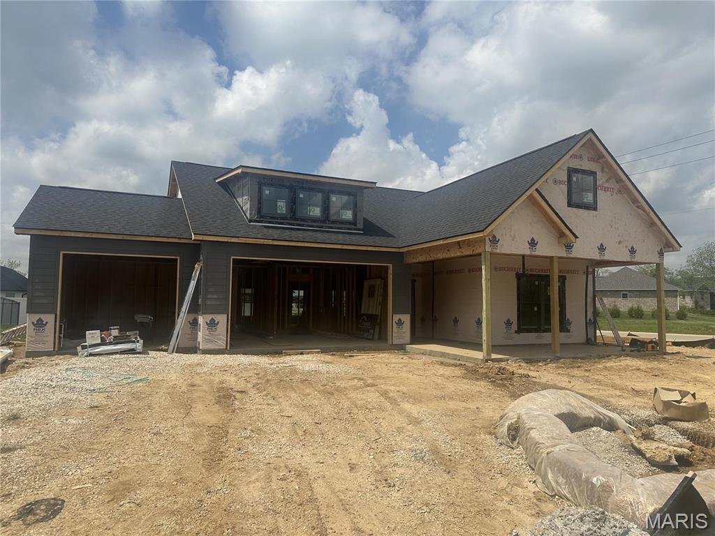 property in mid-construction featuring dirt driveway, an attached garage, and a shingled roof