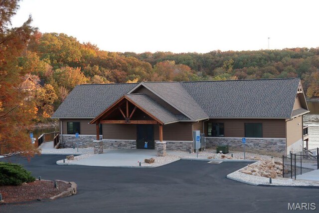 2025 Moat Ln Unit 1513, Marthasville, MO 63357 - view of front of home with stone siding, a wooded view, and a shingled roof