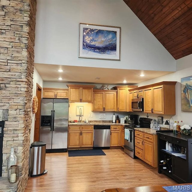 kitchen featuring appliances with stainless steel finishes, high vaulted ceiling, light wood-type flooring, wood ceiling, and brown cabinets