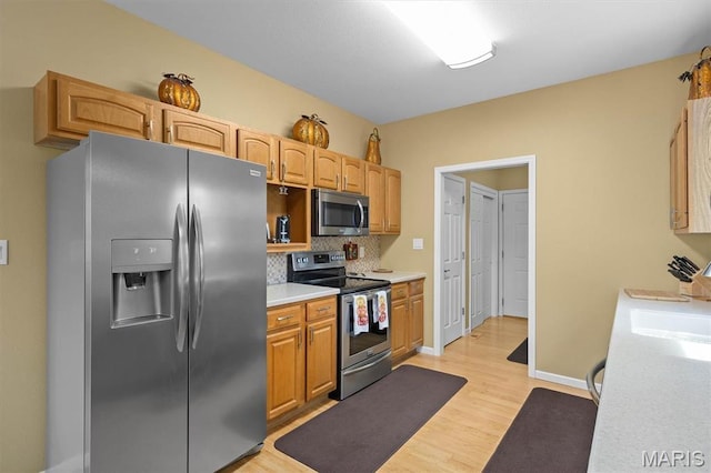 1674 Lakepointe Estates Dr, Ofallon, IL 62269 - kitchen with appliances with stainless steel finishes, light countertops, light wood-type flooring, and decorative backsplash