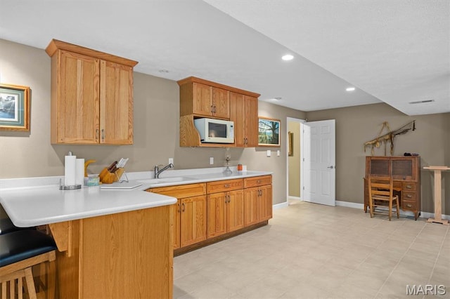 1674 Lakepointe Estates Dr, Ofallon, IL 62269 - kitchen with white microwave, light countertops, a peninsula, a kitchen breakfast bar, and recessed lighting