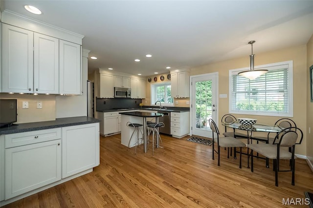 15 York Hills Dr, Saint Louis, MO 63144 - kitchen with stainless steel appliances, white cabinets, light wood-type flooring, dark countertops, and recessed lighting