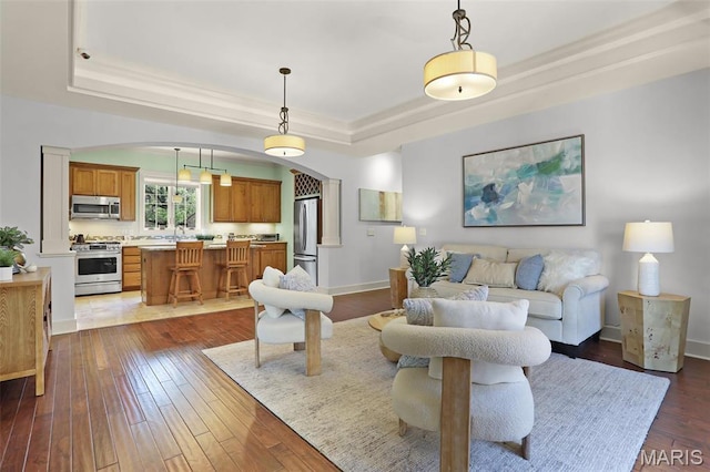 1201 Dolman St, Saint Louis, MO 63104 - living room featuring a tray ceiling, arched walkways, dark wood finished floors, ornamental molding, and baseboards