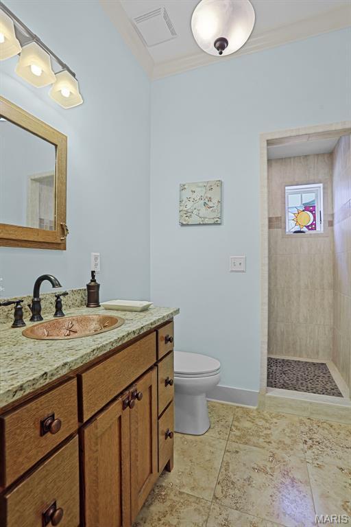 1201 Dolman St, Saint Louis, MO 63104 - bathroom with vanity, toilet, ornamental molding, a tile shower, and baseboards