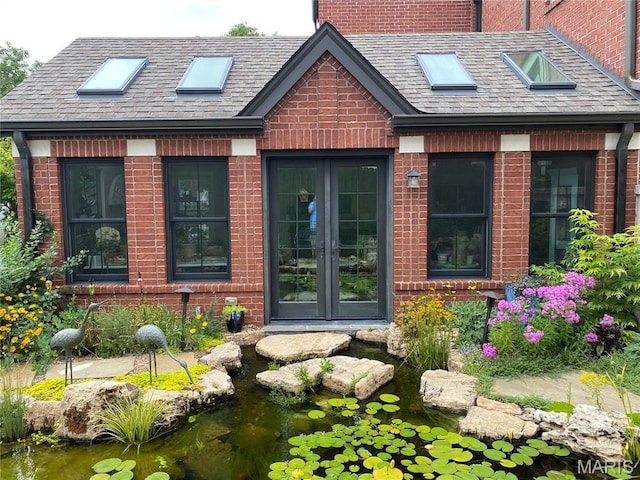 1201 Dolman St, Saint Louis, MO 63104 - property entrance featuring french doors, brick siding, a garden pond, and roof with shingles