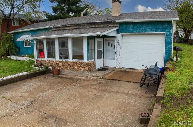 516 N Old Edwardsville Rd, Roxana, IL 62084 - view of front of house featuring a chimney, a garage, a shingled roof, concrete driveway, and a sunroom
