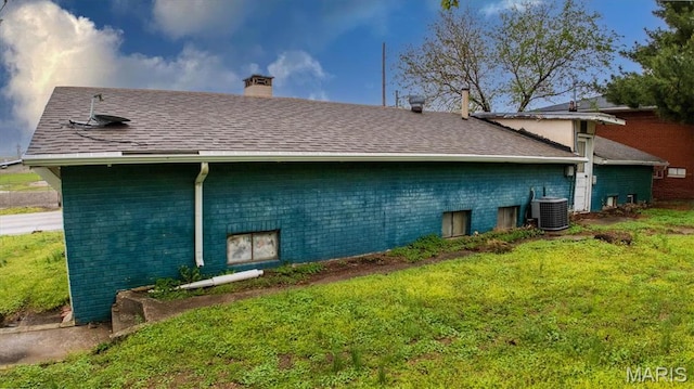516 N Old Edwardsville Rd, Roxana, IL 62084 - view of side of property featuring a chimney, central air condition unit, a yard, a shingled roof, and brick siding