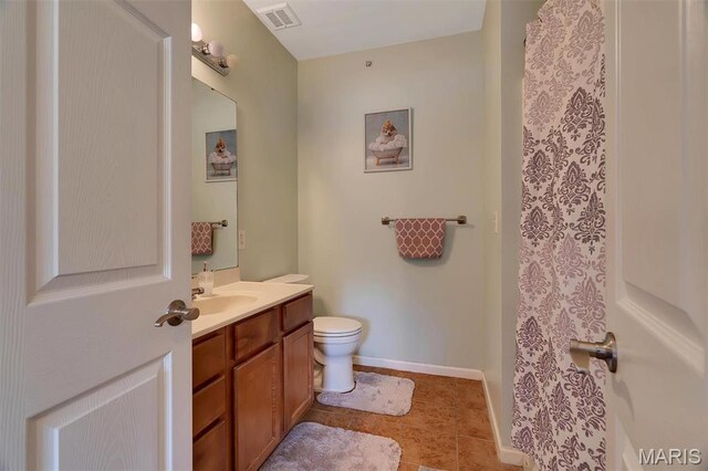 bathroom featuring toilet, vanity, baseboards, and tile patterned flooring