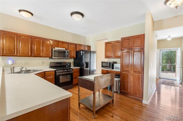 627 Rosetta Dr Unit M1, Florissant, MO 63031 - kitchen featuring appliances with stainless steel finishes, a sink, light countertops, light wood finished floors, and brown cabinetry