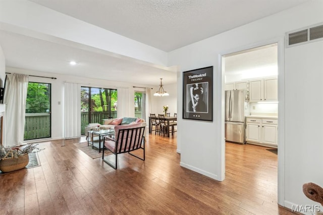 dining area with light wood-type flooring, a chandelier, and baseboards