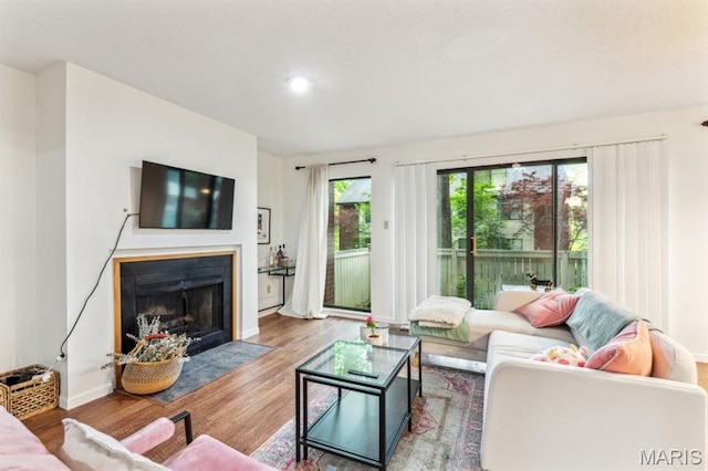 living room featuring wood finished floors, baseboards, a fireplace with flush hearth, and recessed lighting