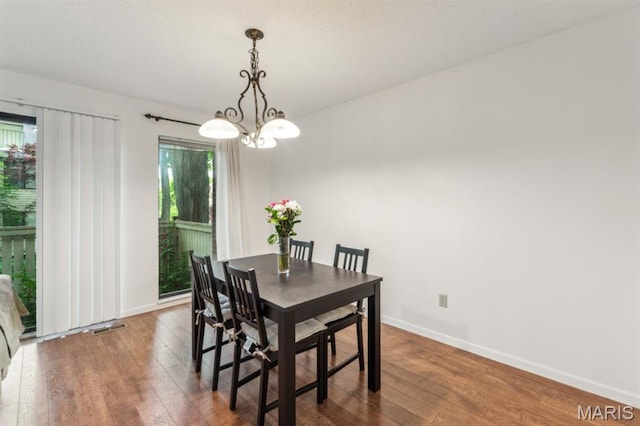 dining area with hardwood / wood-style floors, a chandelier, and baseboards