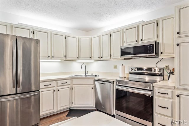 kitchen featuring stainless steel appliances, a sink, a textured ceiling, and light countertops