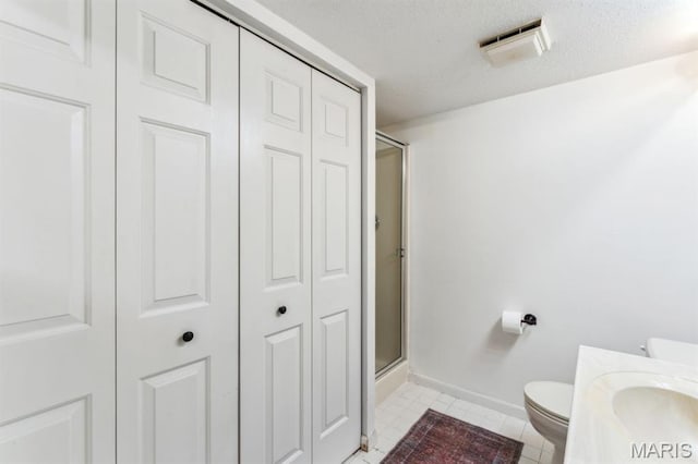 full bathroom featuring a closet, toilet, a shower with door, and a textured ceiling