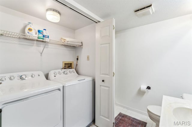 washroom featuring separate washer and dryer, light tile patterned flooring, and baseboards
