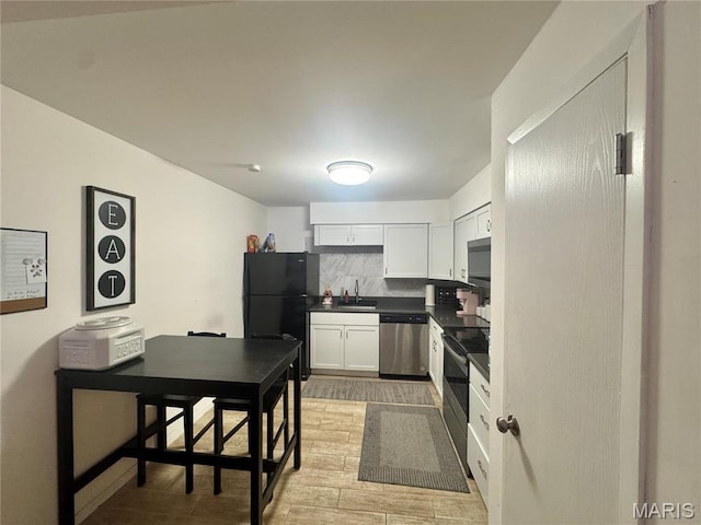 kitchen featuring stainless steel appliances, a sink, dark countertops, white cabinets, and light wood-style flooring