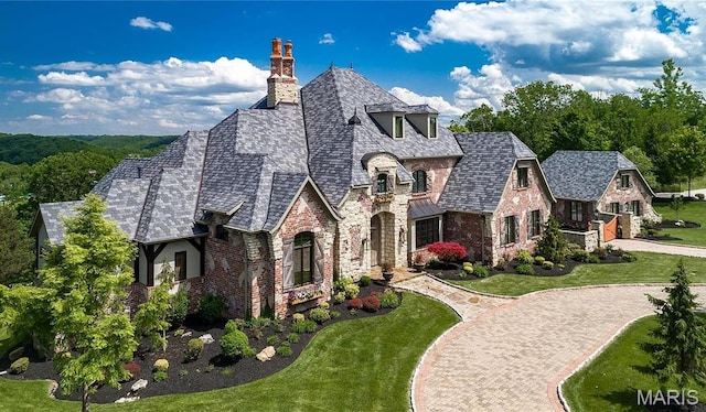 544 Quail Ridge Ln, Saint Albans, MO 63073 - view of front of home with stone siding, a chimney, curved driveway, a front yard, and a high end roof