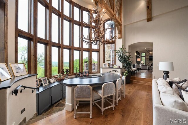 544 Quail Ridge Ln, Saint Albans, MO 63073 - dining room featuring a chandelier, a towering ceiling, healthy amount of natural light, arched walkways, and light wood-type flooring