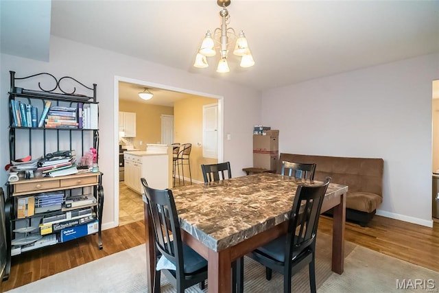 11518 Galba Dr, Florissant, MO 63033 - dining room featuring a chandelier, wood finished floors, and baseboards