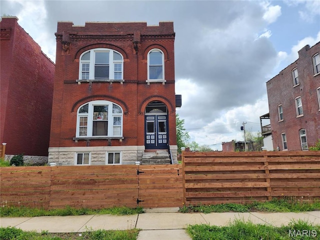 view of front facade featuring brick siding and a fenced front yard