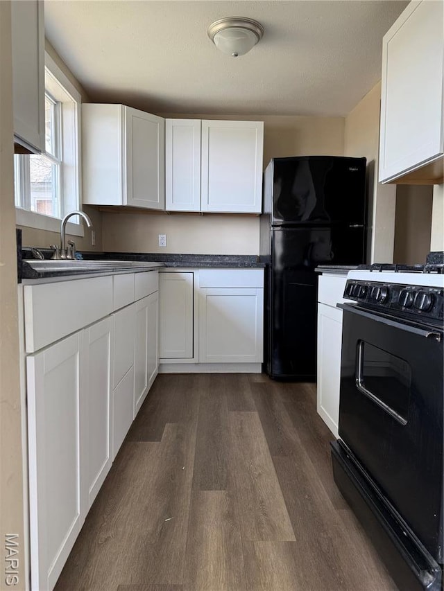 kitchen featuring black appliances, dark wood-style flooring, a sink, white cabinets, and dark countertops