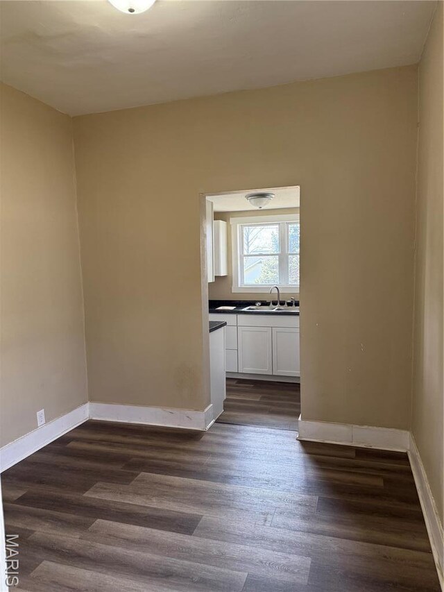 unfurnished room featuring a sink, dark wood finished floors, and baseboards