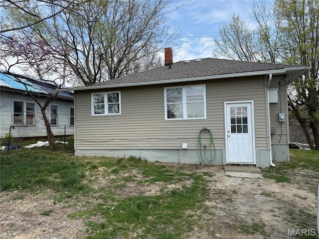 back of property with a chimney and roof with shingles