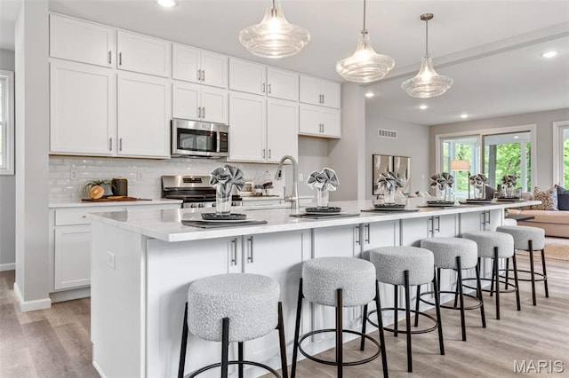 kitchen featuring appliances with stainless steel finishes, light wood-style floors, backsplash, white cabinets, and recessed lighting