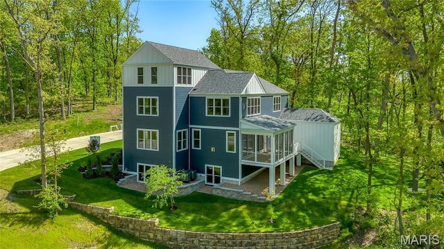 back of property featuring a sunroom, a lawn, and roof with shingles