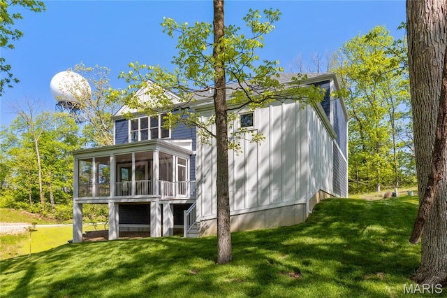 rear view of house featuring a sunroom and a lawn