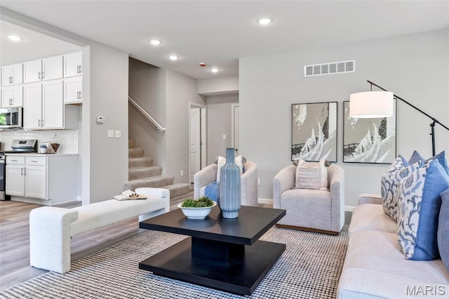 living room featuring stairway, recessed lighting, and light wood-type flooring