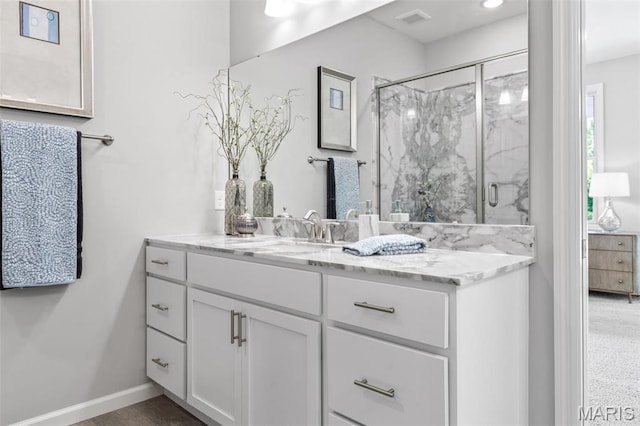 full bathroom with a marble finish shower, vanity, and baseboards