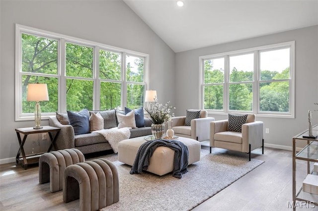 living area with healthy amount of natural light, wood finished floors, baseboards, recessed lighting, and high vaulted ceiling