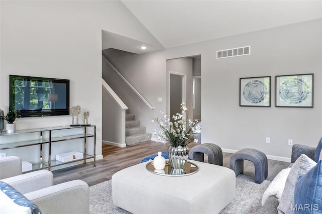 living area featuring wood finished floors, stairs, lofted ceiling, and baseboards