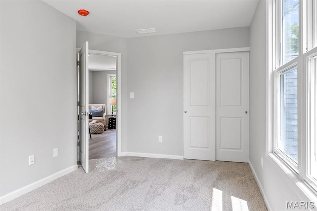 unfurnished bedroom with multiple windows, carpet floors, baseboards, and a closet