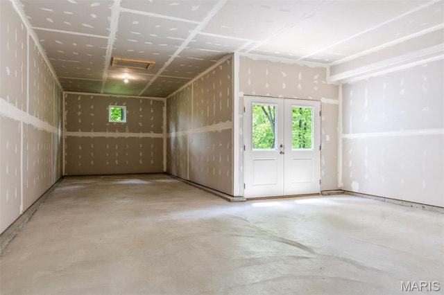 empty room featuring unfinished concrete floors, healthy amount of natural light, and french doors