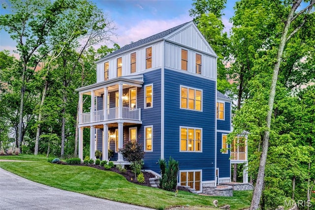view of front of home featuring a balcony, board and batten siding, a yard, and a porch
