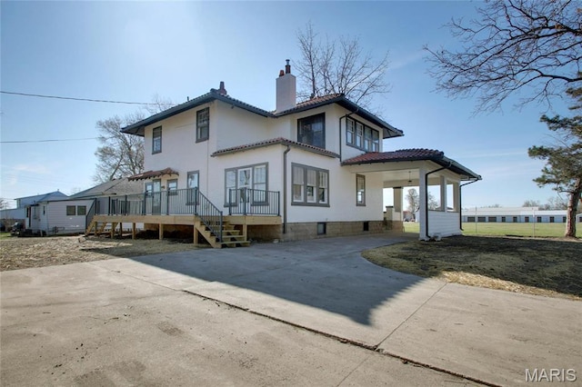 410 White St, Canton, MO 63435 - back of house featuring a chimney, a wooden deck, a tile roof, driveway, and stucco siding