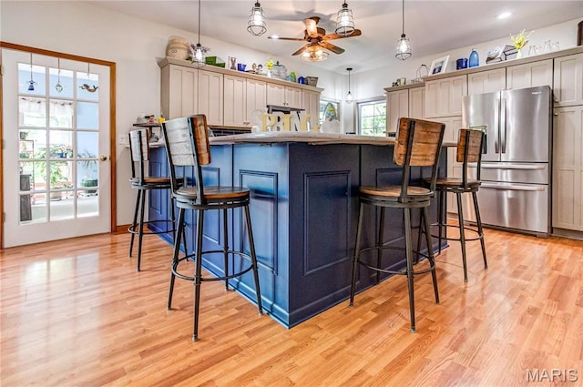 1302 Walnut St, Jerseyville, IL 62052 - kitchen with stainless steel fridge, ceiling fan, a breakfast bar area, light wood-type flooring, and pendant lighting