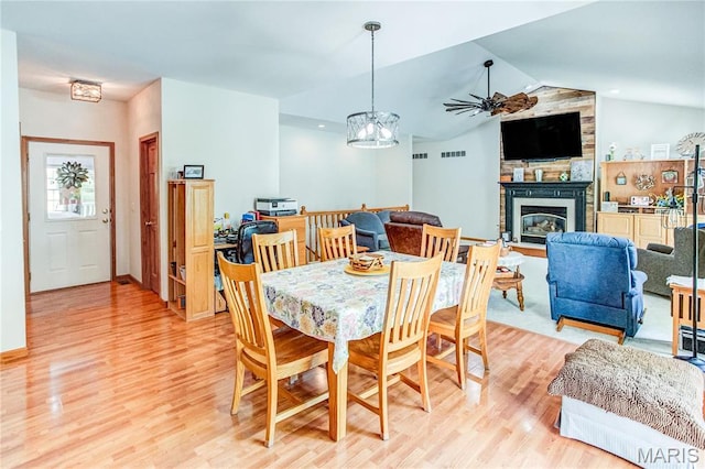 1302 Walnut St, Jerseyville, IL 62052 - dining area with light wood-type flooring, a fireplace, ceiling fan, vaulted ceiling, and a chandelier