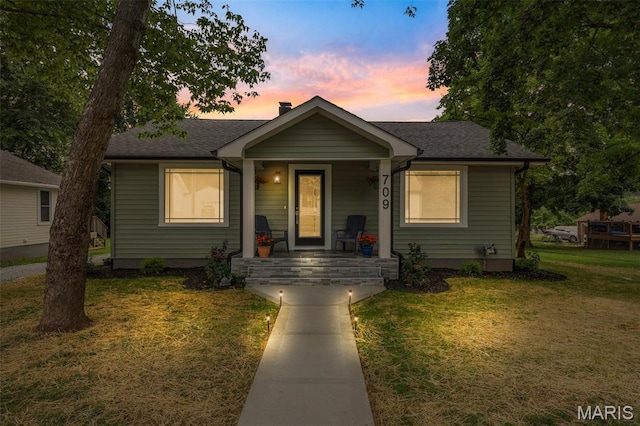 709 Warren St, Farmington, MO 63640 - bungalow-style house with a porch, a lawn, a shingled roof, and a chimney