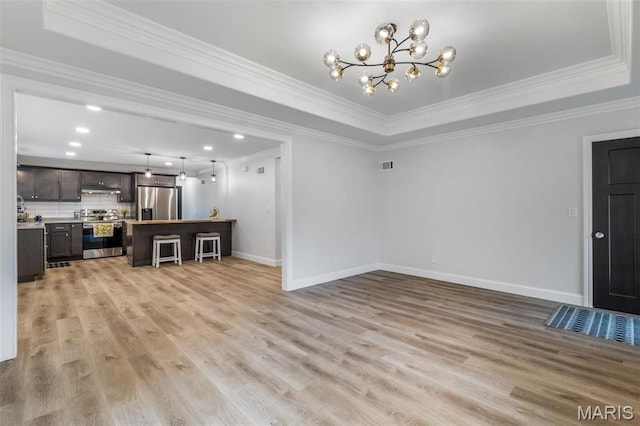 709 Warren St, Farmington, MO 63640 - unfurnished living room with a raised ceiling, light wood-style floors, baseboards, a chandelier, and crown molding