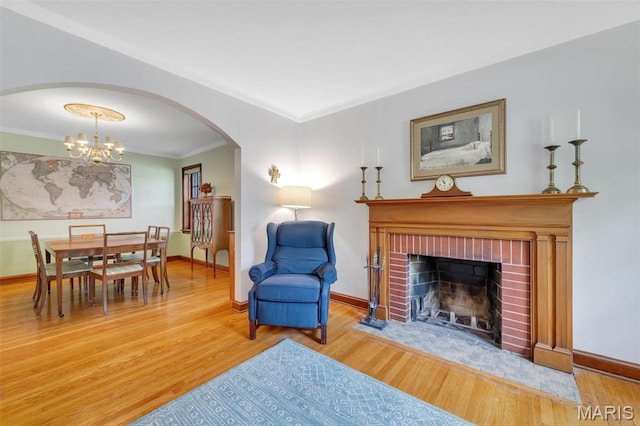 7423 Tulane Ave, Saint Louis, MO 63130 - living room with arched walkways, crown molding, wood finished floors, a chandelier, and a brick fireplace