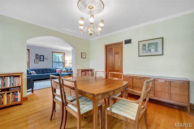 7423 Tulane Ave, Saint Louis, MO 63130 - dining room featuring arched walkways, light wood finished floors, a chandelier, and crown molding