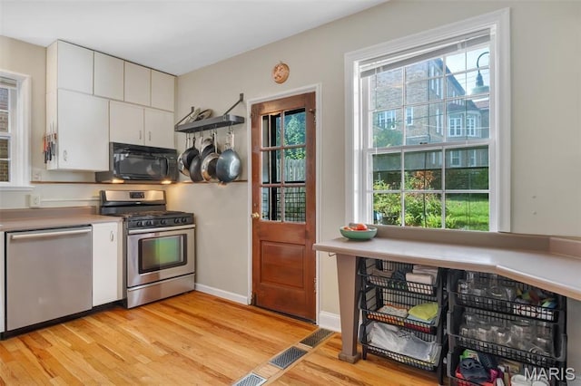 7423 Tulane Ave, Saint Louis, MO 63130 - kitchen with appliances with stainless steel finishes, light wood-type flooring, white cabinets, and light countertops