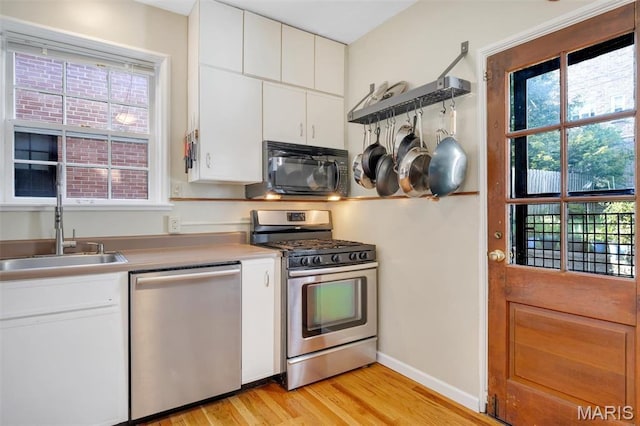 7423 Tulane Ave, Saint Louis, MO 63130 - kitchen featuring appliances with stainless steel finishes, light wood-type flooring, white cabinets, and light countertops