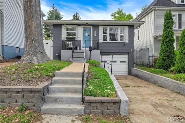 view of front of home with concrete driveway, a garage, and fence