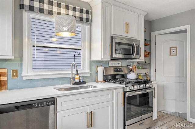 kitchen featuring stainless steel appliances, a sink, white cabinetry, backsplash, and light countertops